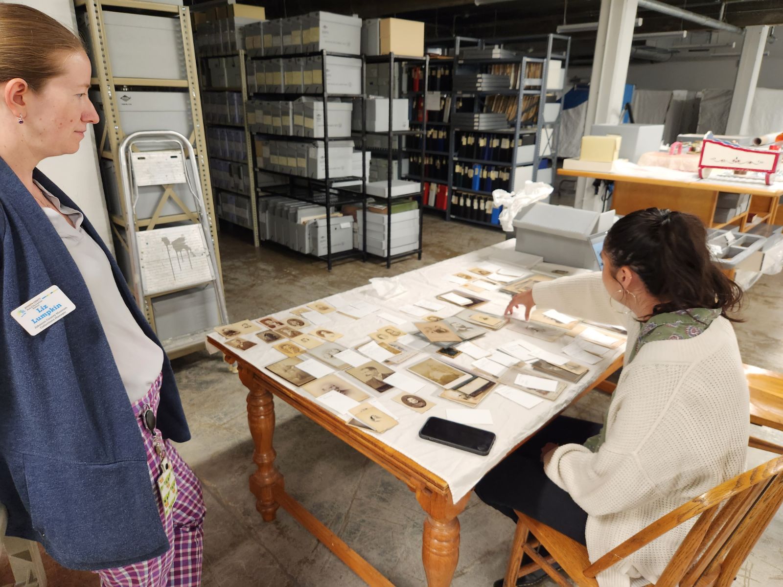Collections Manager Liz Lumpkin and Emerging Museum Professional Intern Jessica Sapien reviewing historical photographs in the Museum’s collection storage room after updating their database information.