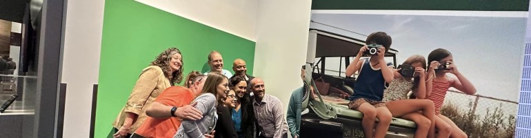 A group of people lean in for a photo at the Museum's green screen photo booth.